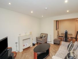 A living room with a sofa, armchair, coffee table, TV, and dining area at Lookout Post in Bridlington