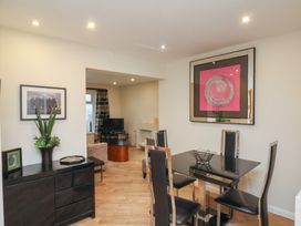 A dining area with black chairs and table next to a living room with a TV and framed art at Lookout Post in Bridlington