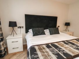 A bedroom with a bed with a dark headboard and patterned bedspread between two white nightstands with black lamps at Lookout Post in Bridlington
