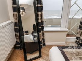 A bedroom with a standing mirror curtains window showing sea view and a radiator at Lookout Post in Bridlington