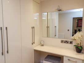 A dressing table with a mirror and stool next to built in wardrobes at Lookout Post in Bridlington