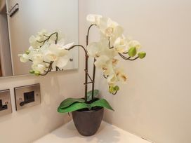 A potted white orchid plant on a countertop next to a wall mirror and electrical outlets at Lookout Post in Bridlington