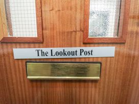 A wooden door with two glass panels a brass mail slot and a label that reads The Lookout Post at Lookout Post in Bridlington