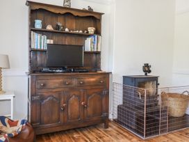A living room with a wooden cabinet and fireplace at Sea Ledge in Tintagel