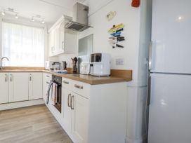 A kitchen with cabinets, sink, and refrigerator at Sea Ledge Tintagel