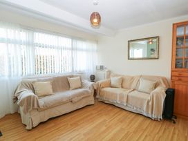 A living room with two covered sofas and a wooden cabinet with glass doors at Chalet 469 Newport Norfolk