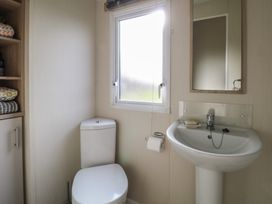 A bathroom with a toilet a sink a mirror and a window at Breathing Space Happisburgh near Walcott