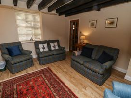 A living room with plaid sofas and armchairs a red rug and a side table with a lamp at Timberwick Green Akeld near Wooler