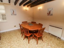 A dining room with a wooden table and six chairs with animal paintings on the walls at Timberwick Green Akeld near Wooler