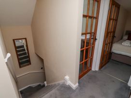 A carpeted staircase with beige walls and a mirror on the wall next to two wooden framed glass doors leading to bedrooms at Timberwick Green Akeld near Wooler