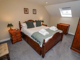 A bedroom with a wooden bed and bedside tables with green lamps at Timberwick Green in Akeld near Wooler