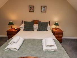 A bedroom with a double bed two pillows two bedside tables with lamps and folded towels at Timberwick Green Akeld near Wooler