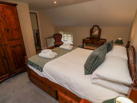 A bedroom with a double bed towels on bed wooden wardrobe chair dressing table and lamp at Timberwick Green Akeld near Wooler