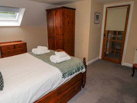 A bedroom with a wooden bed with white linens and green throw with towels on it a wooden wardrobe a wooden chest of drawers a skylight window and a door with a roller blind at Timberwick Green Akeld near Wooler