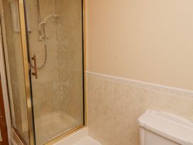 A bathroom with a glass-enclosed shower with patterned glass and a white toilet with tiled walls at Timberwick Green in Akeld near Wooler