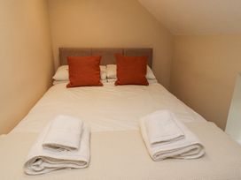 A bedroom with a bed with white sheets two orange pillows and folded white towels on a blanket at Timberwick Green in Akeld near Wooler