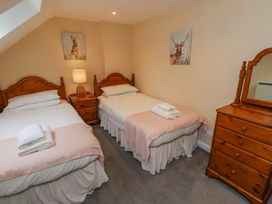 A bedroom with two single beds two animal paintings a wooden dresser and a nightstand with a lamp at Timberwick Green Akeld near Wooler