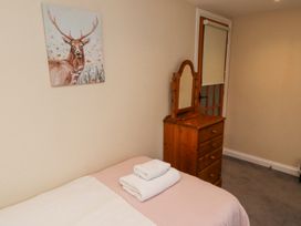 A bedroom with a bed with folded towels on it a wooden dresser with a mirror a door with a roller blind and a painting of a stag on the wall at Timberwick Green Akeld near Wooler