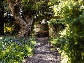 A garden with a stone wall, bench, and flowers at Timberwick Green, Akeld near Wooler
