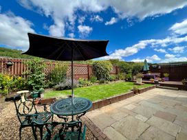 A garden with a table and chairs under an umbrella at Harefield in Rothbury