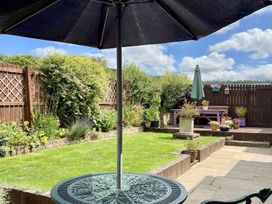 A garden with a table, umbrella, and seating area at Harefield in Rothbury