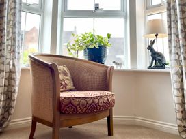 A living room with a chair and a plant on a windowsill at Harefield in Rothbury