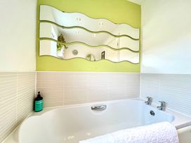 A bathroom with a bathtub and decorative mirror at Harefield in Rothbury