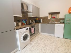 A kitchen with appliances including a washing machine and refrigerator at The Stable in Rosudgeon
