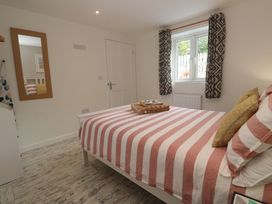 A bedroom with a striped bedspread and a mirror at The Stable in Rosudgeon