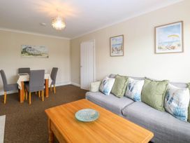 A living room with a gray sofa with cushions and a wooden coffee table with a decorative bowl at Little Lodge in Dersingham