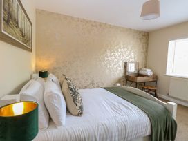 A bedroom with a bed with white linens and green throw at Little Lodge in Dersingham