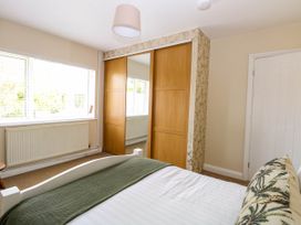 A bedroom with a bed a green blanket a window with blinds a radiator and a mirrored wardrobe at Little Lodge in Dersingham