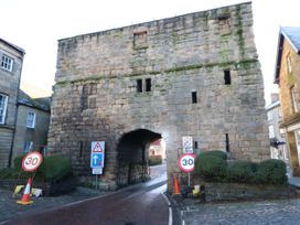 A stone archway with road signs and bushes at Middle Cottage in Alnwick