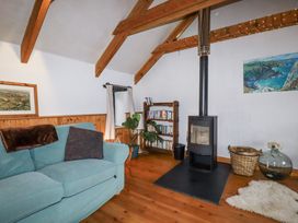 A living room with a wood stove and bookshelves at Coombe Barn in Cusgarne near St Day