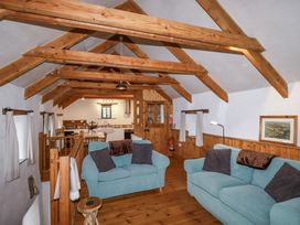 A living room with wooden beams and a kitchen area at Coombe Barn in Cusgarne near St Day