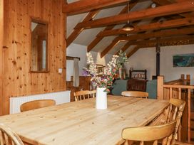 A dining room with a wooden table and flower vase at Coombe Barn Cusgarne near St Day