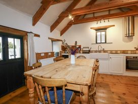 A kitchen with a dining table and wooden chairs at Coombe Barn Cusgarne near St Day