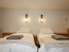 A bedroom with two beds and bedside tables at Coombe Barn in Cusgarne near St Day