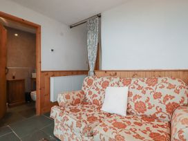 A living room with a sofa and a door leading to the bathroom at Stribleys Barn in Cusgarne near St Day