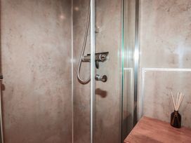 A shower area with a glass panel and wooden surface at Stribleys Barn in Cusgarne near St Day