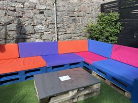 An outdoor lounge area with colorful seating and a table at Delmonte Lodge in Torquay