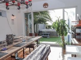 A dining room with a large table and a hot tub visible through the glass doors at Delmonte Lodge in Torquay