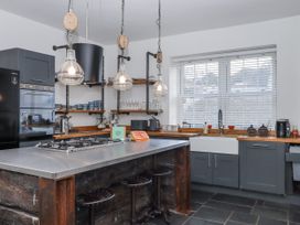 A kitchen with a cooking range and stools at Delmonte Lodge in Torquay