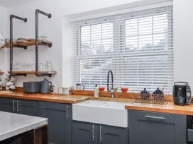 A kitchen featuring a sink, shelves with glassware, and a kettle at Delmonte Lodge in Torquay