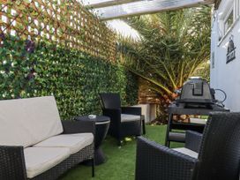 An outdoor seating area with a grill and palm tree at Delmonte Lodge in Torquay