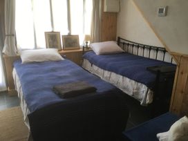 A bedroom with two beds and artwork on the walls at Pit Paddy Barn Cusgarne near St Day