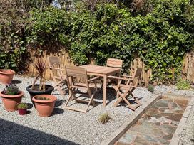 A garden with a table and chairs surrounded by potted plants at Falmouth Bay 1, Falmouth