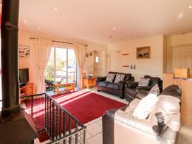 A living room with three leather sofas a red rug a wood stove and sliding glass doors at Swallow Barn in Holton near Halesworth