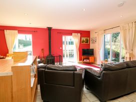 A living room with two dark sofas a wood stove and a television on a wooden stand at Swallow Barn Holton near Halesworth