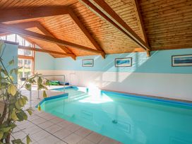An indoor swimming pool with handrails and framed pictures on the wall at Swallow Barn in Holton near Halesworth